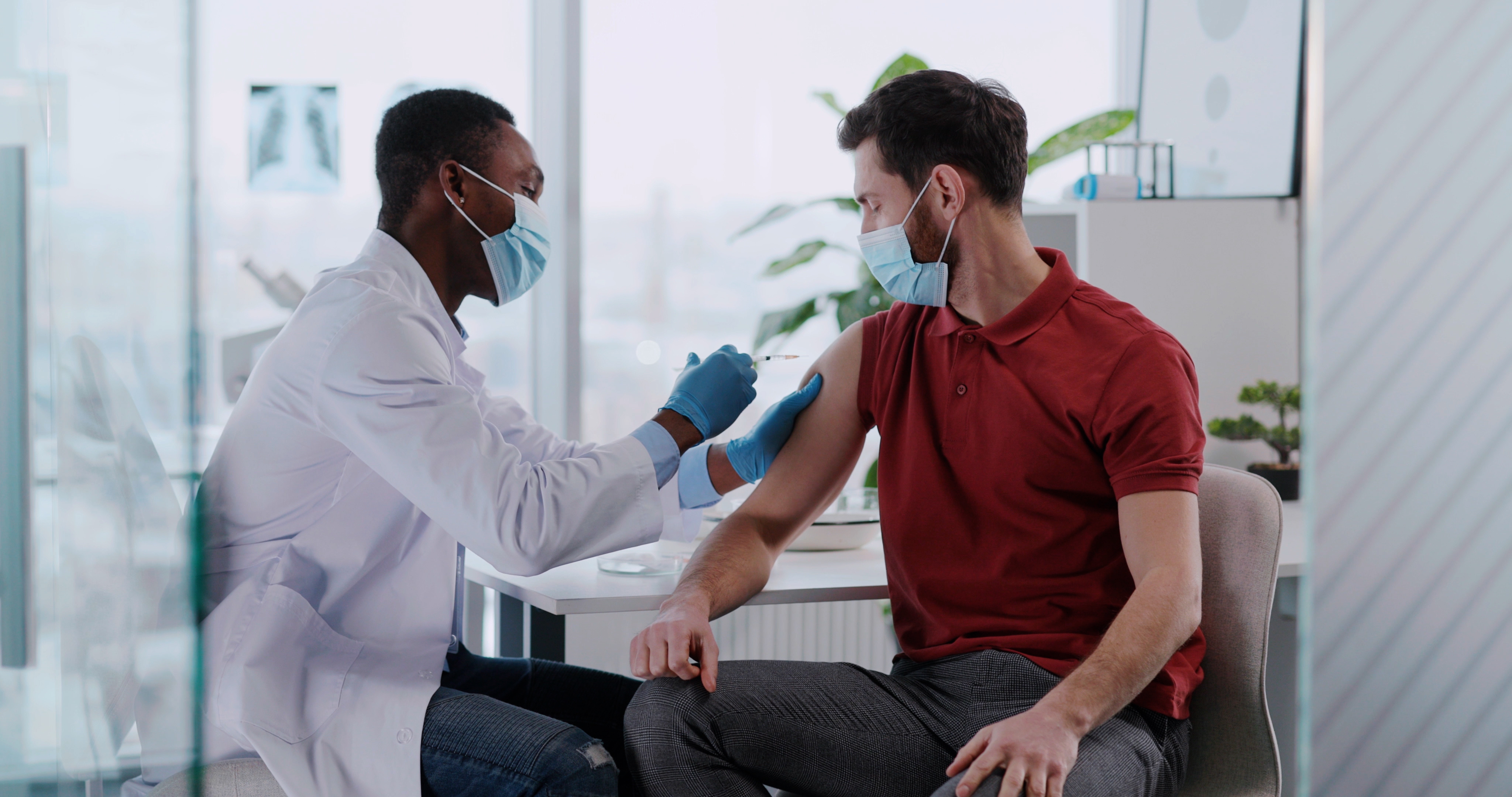 A clinician administers a flu shot to a patient's upper arm during a clinic visit