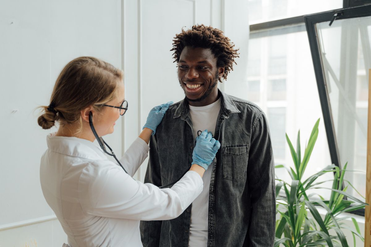 A doctor examining a smiling patient with a stethoscope during a walk-in clinic visit